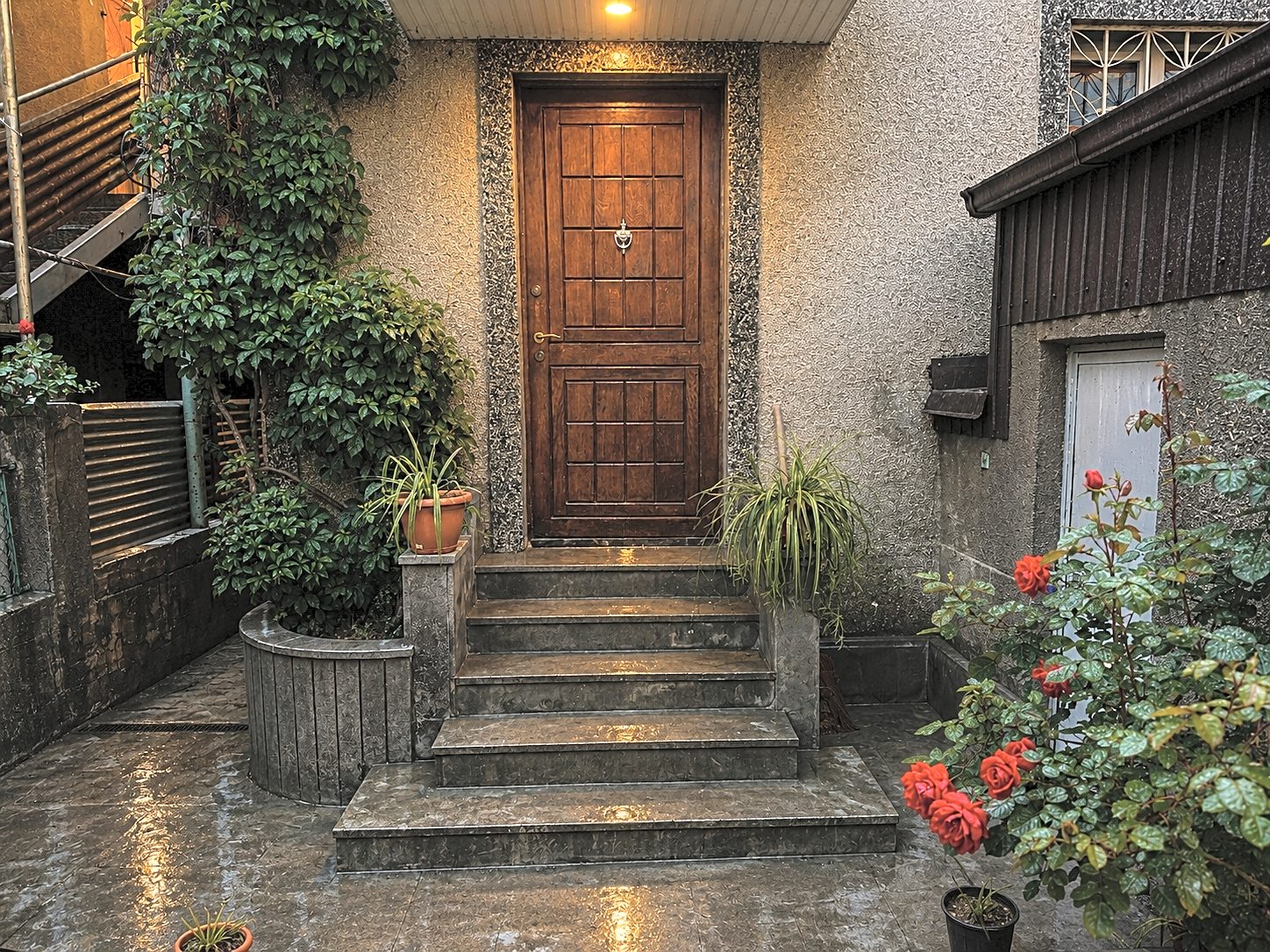 The carved wooden front door at dusk with roses on the steps