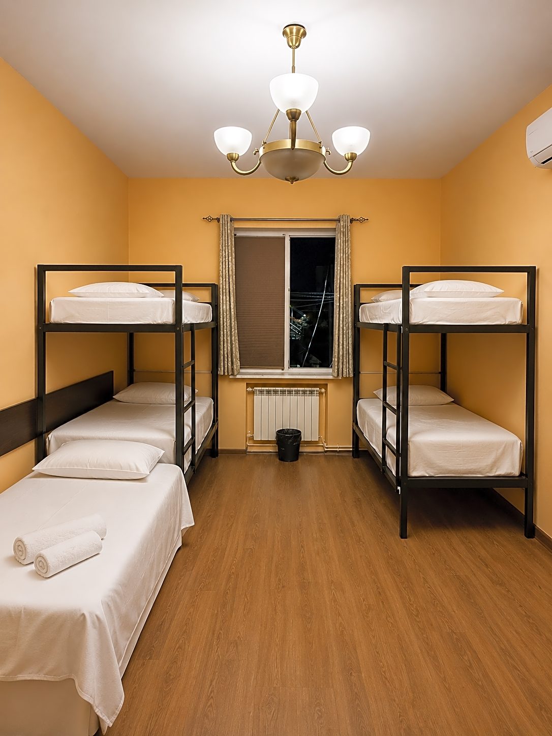 Bright dorm room with black bunk beds, white bedding and a chandelier
