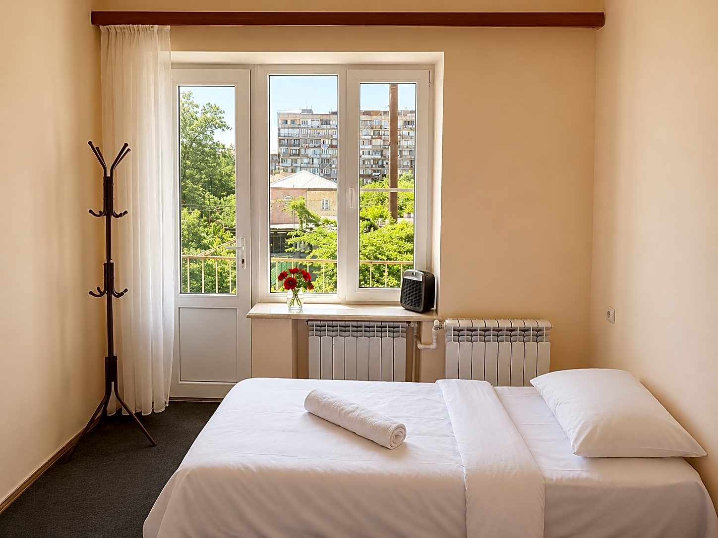 Quiet single room with white bed and a window overlooking the garden