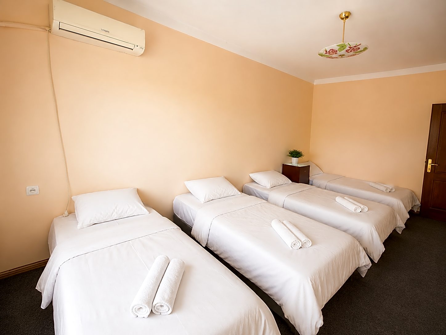 Small bright room with two neatly made white beds and peaches on the table